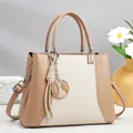 Elegante bolso de mano en cuero caqui y lona patchwork con detalle de colgante redondo - Caqui