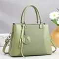 Detalle de bolso de mano verde claro con textura de tela y colgante de béisbol decorativo - Verde
