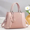 Detalle de bolso rosa con textura tejida, asa redonda y amuleto decorativo de pompón - Rosa