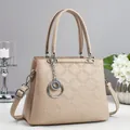 Dettaglio borsa beige in pelle trapuntata con ciondolo ad anelli e trama elegante - Cachi