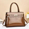 Detailed close-up of brown crocodile texture and gold metallic clasp on tote bag - Brown