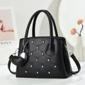 Elegant black leather handbag with diamond quilting, rhinestones, and heart pendant - Black