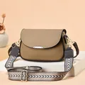Detailed view of tan pebble leather crossbody bag with geometric wide strap on white stand - Khaki