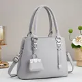 Detailweergave van lichtgrijze leren shopper met mini-tasbedeltje als accessoire - L25 H20 B11 / Grijs