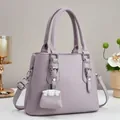 Detailed view of the lychee texture leather on this lilac tote bag with elegant charms - 25cmx20cmx11cm / Purple