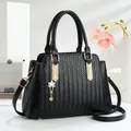 Borsa nera con trama intrecciata, finiture dorate e ciondolo a fiore su sfondo bianco - Nero