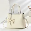 Borsa a mano minimalista beige in similpelle a grana con ciondolo a fiocco e catena d'argento - Avorio