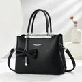 Black litchi pattern leather handbag with pearl bow pendant and detachable strap - Black