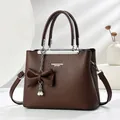 Detail of dark brown lychee leather handbag featuring pearl chain and bow charm - Coffee