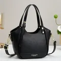 Classic black leather handbag with gold hardware and adjustable crossbody strap - Black