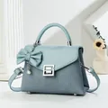Detail of blue textured crossbody bag with silver lock, pearl charm and bow accessory - 22cmx9cmx16cm (Handle 7cm) / Blue