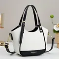 Close-up of contrast leather handbag with gold hardware and logo on pebble texture - White