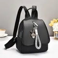 Fashionable black casual backpack with bunny charm and decorative strap on a desk - Black