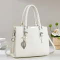 Détail d'un sac à main blanc texturé litchi avec ferrures argentées et pendentif feuille - Blanc