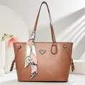 Detail of brown tote bag featuring litchi texture leather and decorative silk scarf - Pink