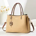 Detail der eleganten beige Handtasche mit braunen Griffen und Blumendekoration - Beige