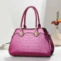 Magenta handtas met krokodillenreliëf, elegante gouden schelpdetails en stevige handgrepen - Paars