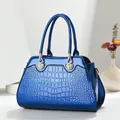 Detail van helderblauwe handtas met reliëf en goudkleurige schelpvormige metalen delen - Blauw