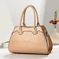 Detail van abrikooskleurige tas met krokodillenpatroon, glanseffect en gouden gespen - Khaki