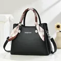 Detail of black pebbled leather handbag with silver logo and decorative silk scarf wrap - Black
