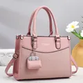 Detail of soft pink tote bag featuring woven leather texture and silver metal hardware - Pink