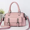 Close-up of pink lychee leather handbag with metallic rivet details and floral decor - Pink