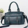 Detail of teal pebble leather handbag featuring vintage rivets and canvas shoulder strap - Blue