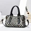 Details der Handtasche mit Leopardenmuster, glänzender Textur und Goldbeschlägen - Schwarzer Leopard