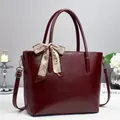 Macro detail of wine red PU leather tote bag with printed silk scarf on handle - Red
