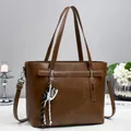 Detail of brown PU leather tote bag with decorative tassel and silver metal hardware - Brown