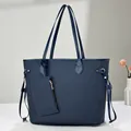 Detail of navy blue tote bag with gold hardware and a matching small zipper pouch - Blue
