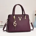 Détails du sac fourre-tout violet foncé en cuir grainé avec logo V doré et breloque - Violet