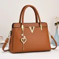Détail du sac en similicuir caramel avec logo V et breloque en forme de cœur perlé - Orange