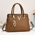 Détail du sac cabas caramel grainé avec logo V doré et breloque cœur en perle - Marron