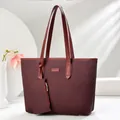 Detail of burgundy tote bag with woven texture, fashion label and gold hardware - Red