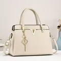 Sac fourre-tout crème chic avec logo V doré et breloque cœur dans un intérieur élégant - Blanc Cassé