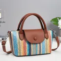 Striped woven crossbody bag with brown leather handles and strap on white tabletop - Blue