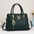 Détail du cabas en cuir grainé vert foncé avec logo V doré et breloque en perles - Vert clair