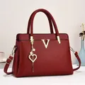 Détail d'un sac à main rouge en cuir avec logo V doré et pendentif cœur en perles - Rouge