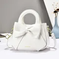 Sac à main blanc en simili cuir avec grand nœud et détails dorés sur fond bleu clair - Blanc
