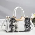 Détail de l'élégant gaufrage motif python et du charm nœud en perles sur le sac à main - Blanc