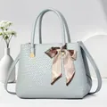 Detail view of a light blue textured tote bag with a decorative silk scarf bow detail - Blue