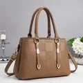 Brown handbag with geometric embossed pattern and adjustable shoulder strap on gray background - Khaki