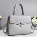 Detail of grey leather tote with litchi texture and gold metal twist-lock clasp - Gray