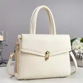 Close-up of minimalist off-white pebble leather handbag featuring a refined golden twist lock - Off White