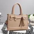Dettaglio borsa beige con trama intrecciata, fiocco e tracolla geometrica larga - Cachi