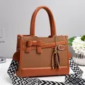 Brown woven texture handbag with leather bow detail and geometric patterned shoulder strap - Earthy Yellow