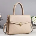 Detail of beige lychee leather handbag featuring gold metal clasp and diamond lattice pattern - Apricot