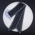 Élégant foulard twilly noir à pois blancs et bords biseautés posé sur une assiette - Pois Blancs sur Fond Noir (C116-2)