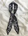 Eleganter schmaler Schal mit Leopardenmuster in Grau und Schwarz auf weißem Seidenhintergrund - Grau-weißes Leopardenmuster